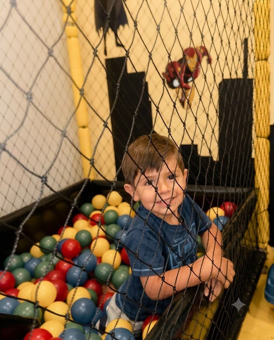 Criança sorrindo na piscina de bolinhas temática de super-heróis