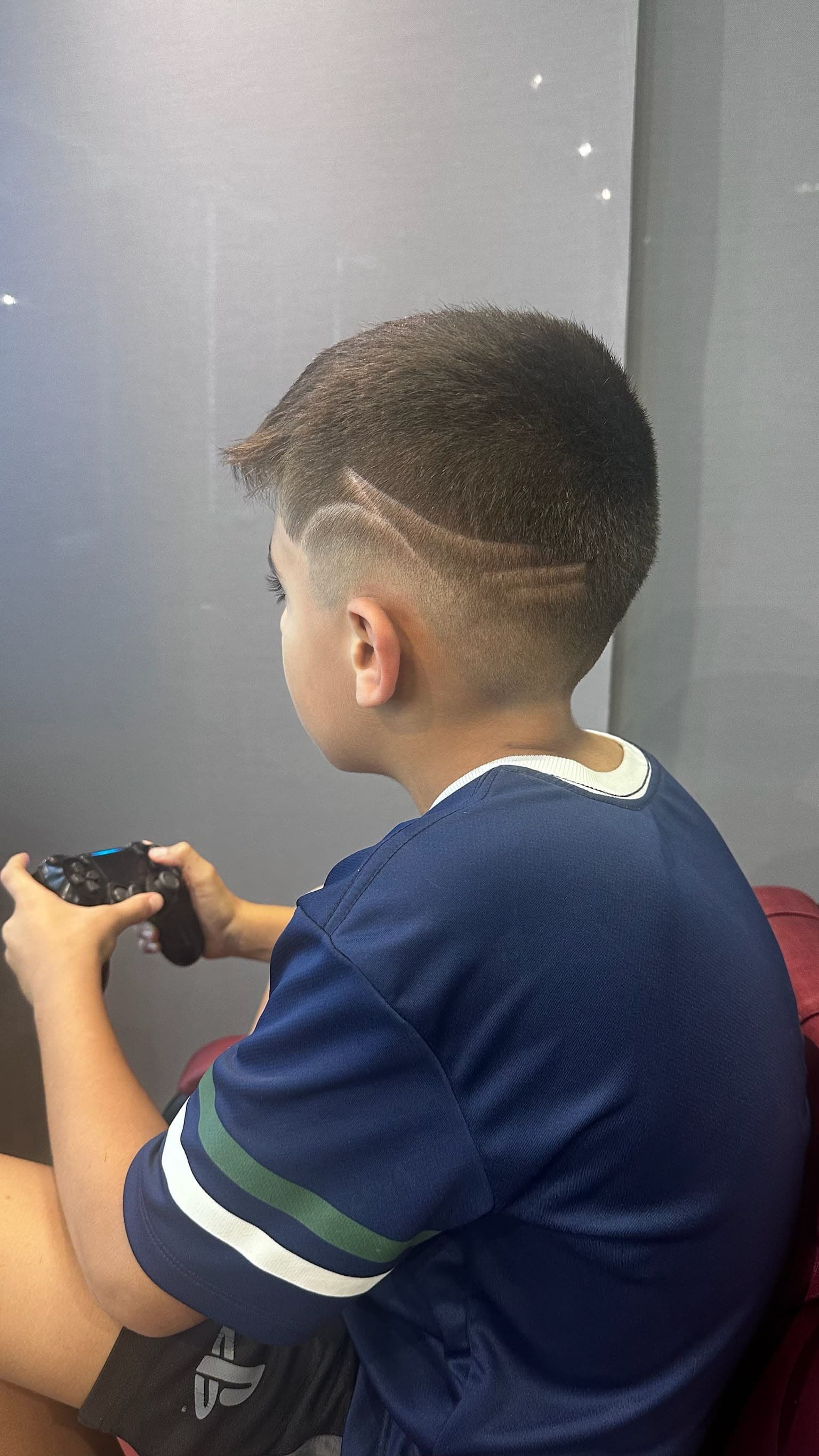 Desenho raspado no cabelo enquanto a criança joga videogame