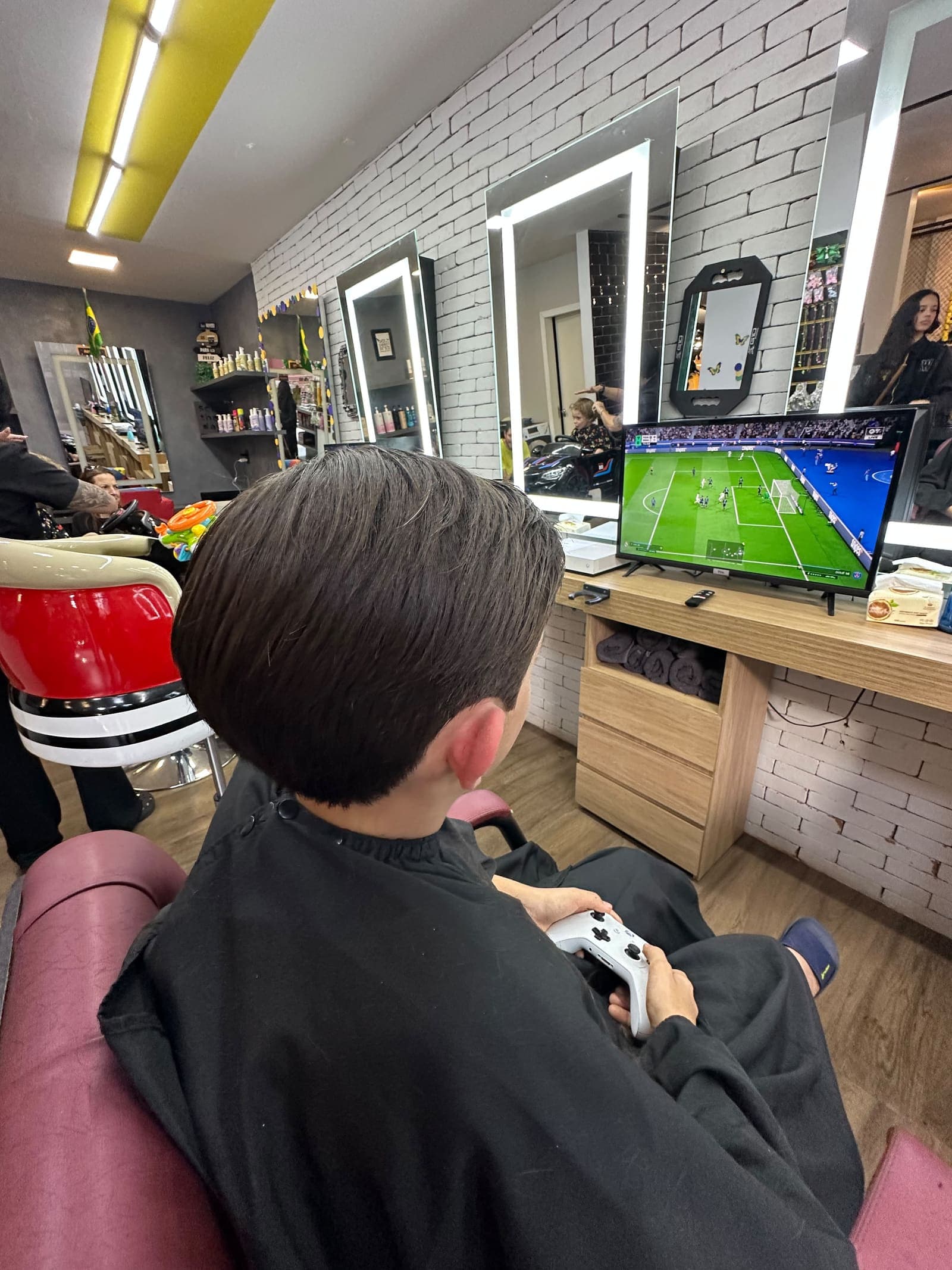 Criança jogando videogame enquanto corta o cabelo